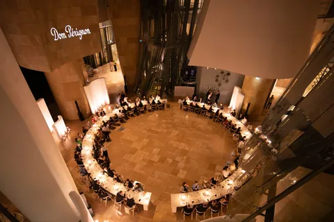 Dom Pérignon Révélations 2026: mesa redonda de la cena vista desde arriba, invitados a la luz de las velas bajo el rótulo Dom Pérignon